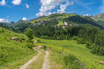 happy senior woman riding her electric mountain bike up to thr famous mountain village of Damuels in the Bregenz Forest mountain of Vorarlberg, Austria