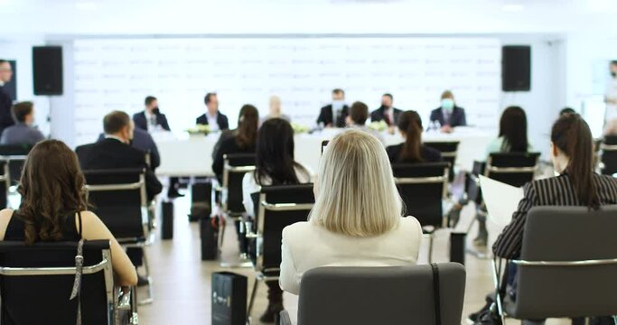 People are sitting on chairs at the conference and listening to the lecturer. Back view. Education concept.