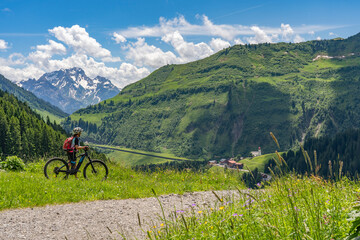 happy senior woman riding her electric mountain bike up to thr famous mountain village of Damuels in the Bregenz Forest mountain of Vorarlberg, Austria