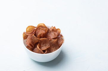 Dried pork chips in a white bowl.