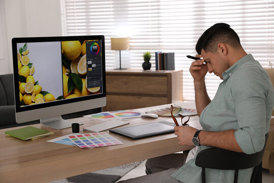 Tired retoucher at workplace with computer in office