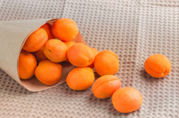 Ripe juicy apricots spilling out of a paper bag on a towel.