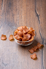 Jerky in a glass bowl on a wooden background.