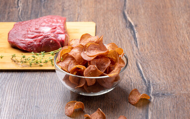 Selective focus on jerky in a glass bowl on a wooden background.