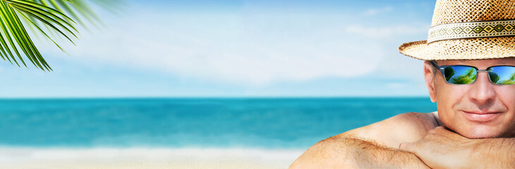 Obraz premium A man is resting on the a seascape background and looking to the camera.