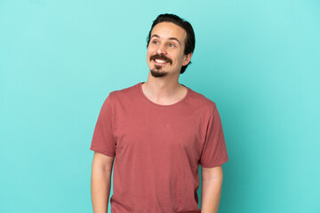 Fototapeta premium Young caucasian man isolated on blue background thinking an idea while looking up