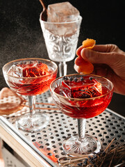Close up bartender squeezing an orange on a cocktail on a black background