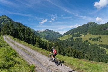 happy senior woman riding her electric mountain bike up to thr famous mountain village of Damuels in the Bregenz Forest mountain of Vorarlberg, Austria
