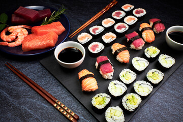 Fish sushi and vegetable sushi with chopsticks, soy sauce and a plate with ingredients
