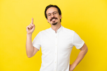 Fototapeta premium Young caucasian man isolated on yellow background showing and lifting a finger in sign of the best