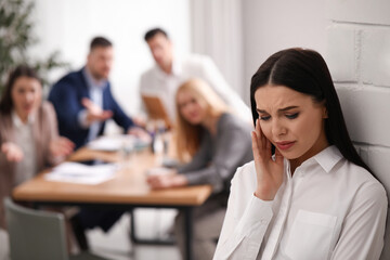 Fototapeta premium Coworkers bullying their colleague in office, space for text