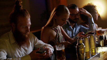 Young bored people using smartphone while sitting in modern bar