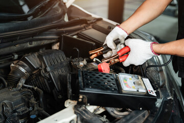 Obraz premium Close up hand of Car repairman with multimeter device for check up car battery life, battery inspection