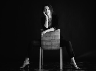 Beautiful woman sits on a chair and looks at you