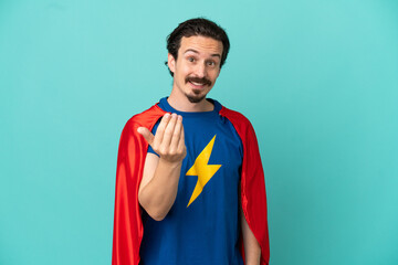 Super Hero caucasian man isolated on blue background inviting to come with hand. Happy that you came