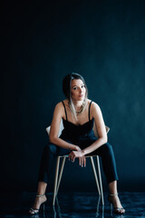 Beautiful woman sits on a chair and looks at you