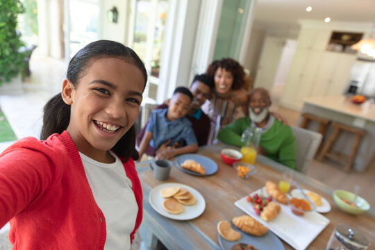 Happy african american family sitting at breakfast table taking selfie and smiling