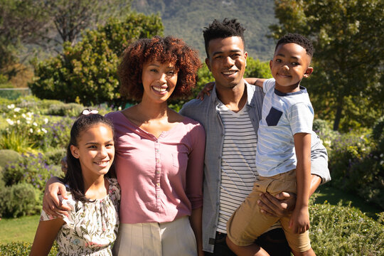 Portrait of happy african american couple with son and daughter outdoors, smiling in sunny garden