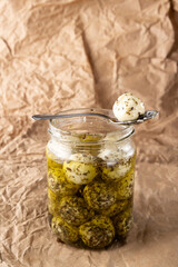 Vertical image of glass bottle of mozzarella with spices,spoon on the rustic paper surface