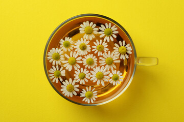Cup of chamomile tea on yellow background