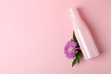 Blank bottle of shampoo and flower on pink background