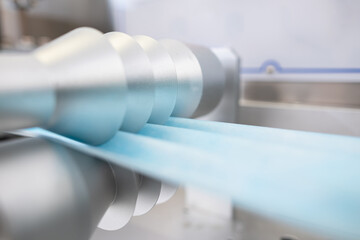 Closeup process of medical face masks being made in a factory. Automated machinery making respiratory medical masks in large quantities.