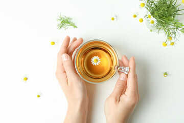Female hands and chamomile tea on white background