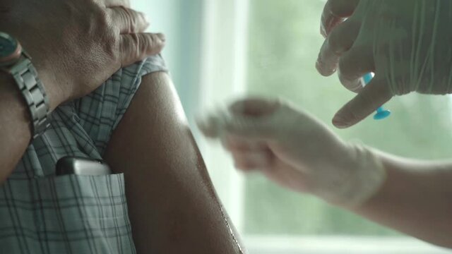 A female doctor vaccinates an elderly man against the coronavirus.