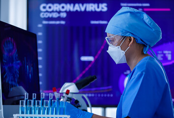 Researcher or scientist holding Covid-19 blood test tube and working with computer screen for analyzing and study about coronavirus in the laboratory