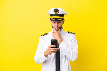 Airplane caucasian pilot isolated on yellow background thinking and sending a message