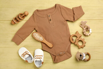 Flat lay composition with baby clothes and accessories on yellow wooden table