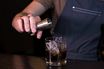 Hands of the bartender close up who make a cocktail white russian