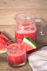 Glass of watermelon smoothie on a wooden table. Selective focus