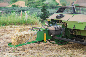 Tractor with harvester attach, harvesting hay crops, creating haystacks on field