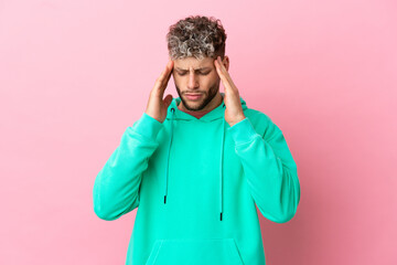 Young handsome caucasian man isolated on pink background with headache