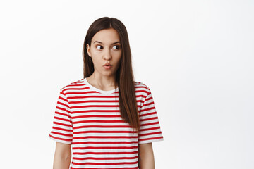 Shocked brunette girl gasping, look right at empty space with speechless startled expression, checking out smth impressive, standing against white background