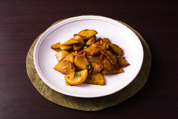 plate with salt and pepper potatoes over dark wooden table.