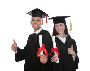 Happy students in academic dresses with diplomas on white background