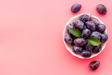 Food layout with plums in bowl with leaves. Top view