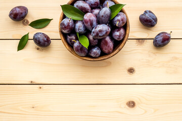 Ripe garden plums in bowl. Cherry fruit with leaves. Top view
