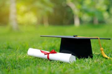 Graduation, Close Up certificate paper, and education cap on green grass springtime in the outdoor park. Concept education congratulation.