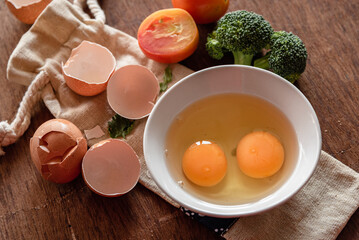 Broken egg shells and yolk eggs on plate at wooden background