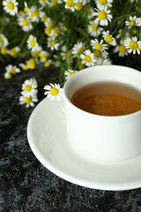 Cup of chamomile tea on black smokey table