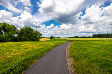 Weiter Blick über das Land mit Radweg weißen Wolken und blauem Himmel