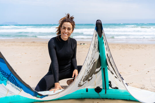 Sportswoman with power kite and kitesurfing equipment on sea shore