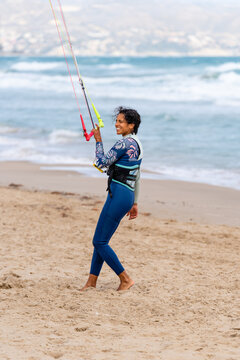 Content ethnic sportswoman holding bar with lines on sea coast