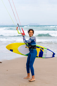 Content ethnic sportswoman holding bar with lines on sea coast
