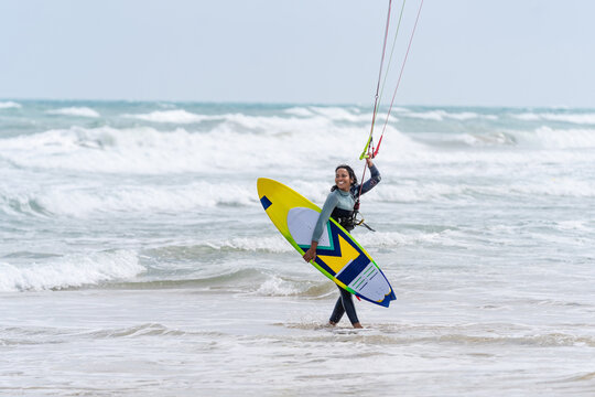 Kitesurfer with kiteboard on sea coast in stormy weather