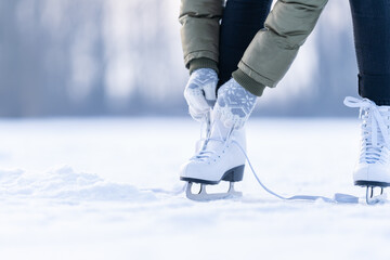 tying the laces of winter skates on a frozen lake, ice skating