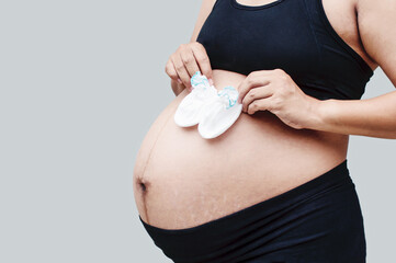 Close up of pregnant belly. Young beautiful pregnant woman standing on white background. Beautiful tender mood photo of pregnancy.